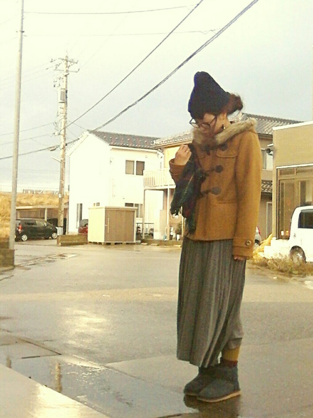 イエロー系のダッフルコート、グレー系のスカート、ブルー系のブーツを着用したレディースの冬コーディネートの1枚目の写真