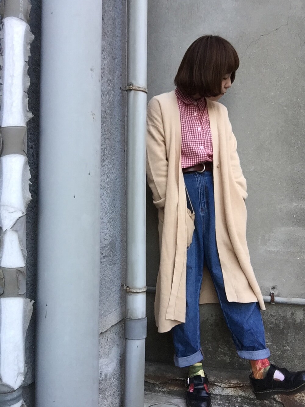 ベージュ系のカーディガン/ボレロ、レッド系のシャツ/ブラウス、ブルー系のデニムパンツを着用したレディースの春コーディネートの1枚目の写真