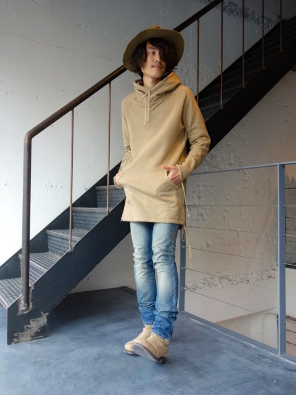 ベージュ系のパーカー、ブルー系のデニムパンツ、ベージュ系のハットを着用したメンズの秋コーディネートの1枚目の写真