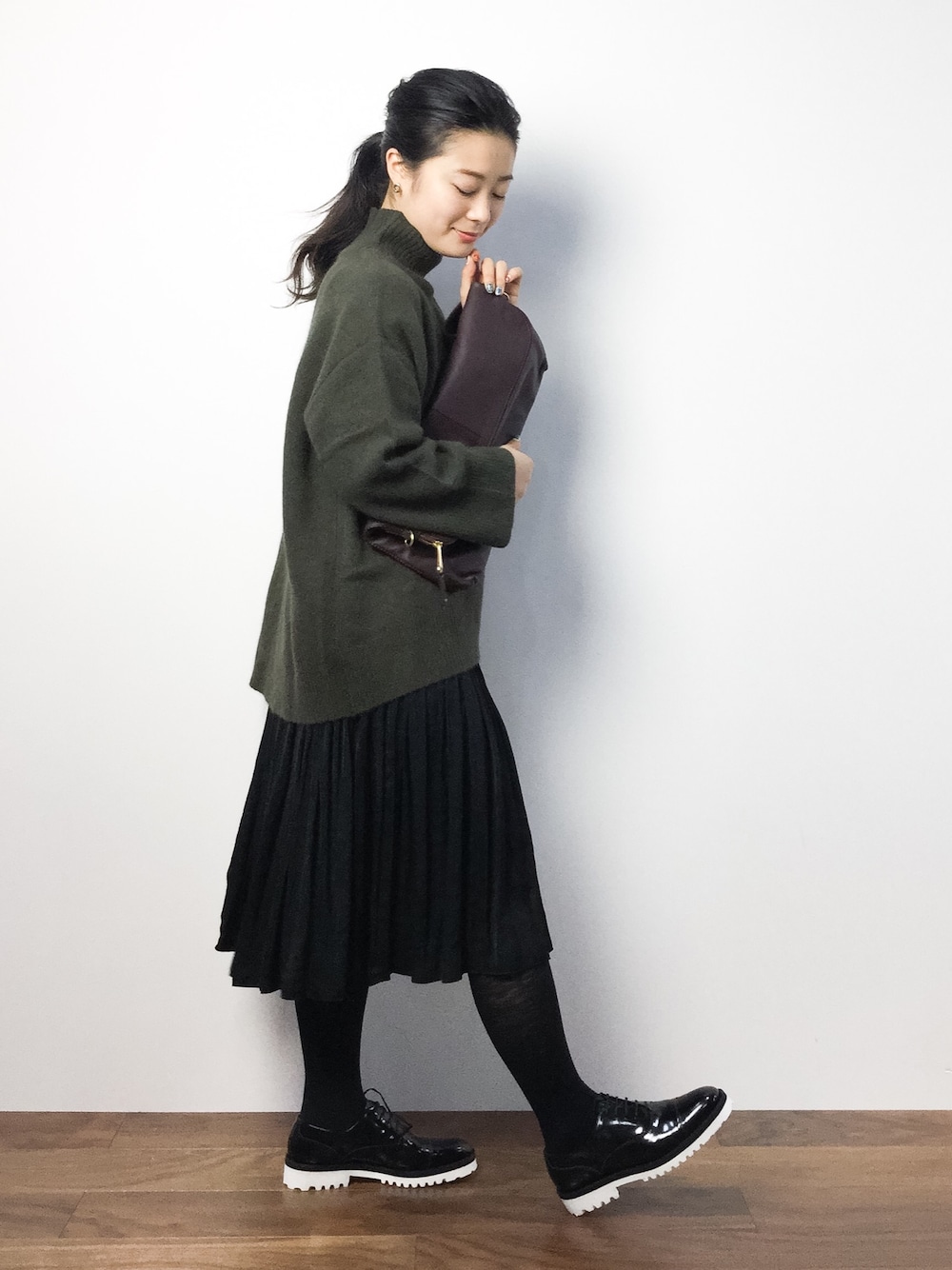 グリーン系のニット/セーター、ブラック系のスカート、ブラック系のドレスシューズを着用したレディースの秋コーディネートの1枚目の写真