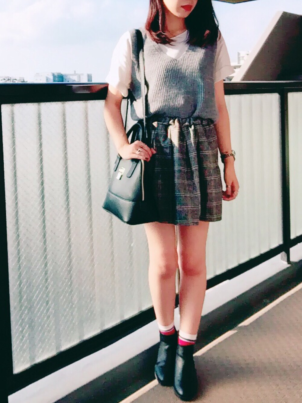 ブラック系のバッグ、グレー系のベスト、ブラック系のシューズを着用したレディースの秋コーディネートの1枚目の写真