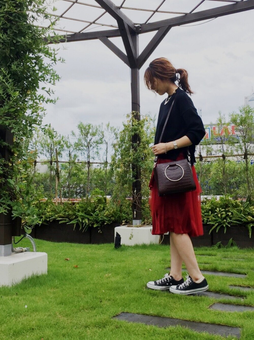 ブラック系のニット/セーター、ブラウン系のトートバッグ、レッド系のスカートを着用したレディースの秋コーディネートの1枚目の写真