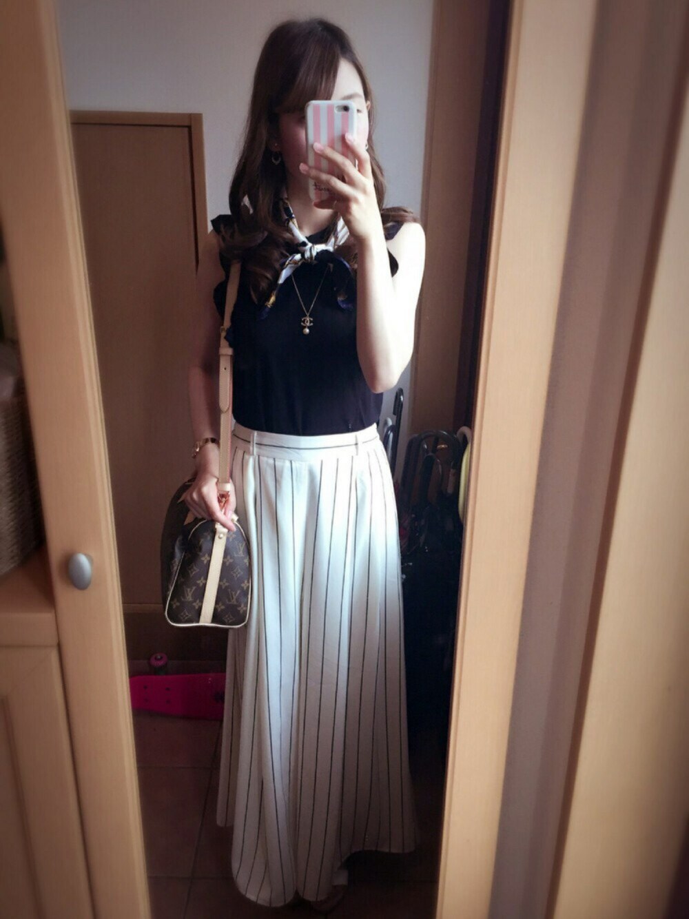 ブラック系のトップス、ホワイト系のパンツ、ブラウン系のバッグを着用したレディースの夏コーディネートの1枚目の写真