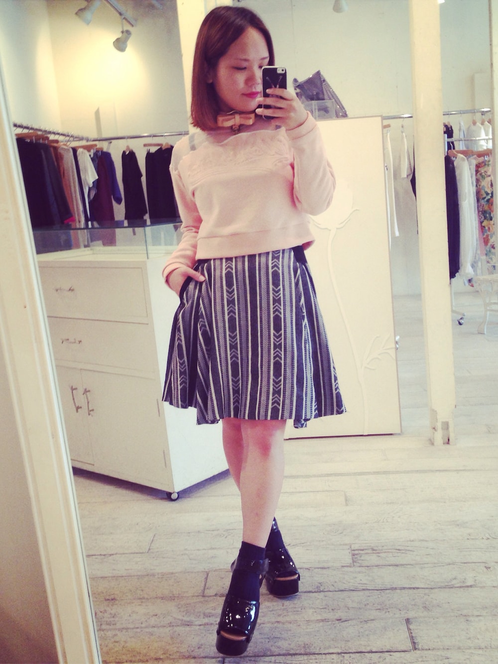 ブラック系のスカート、ブラック系のサンダル、ホワイト系のトップスを着用したレディースの春コーディネートの1枚目の写真