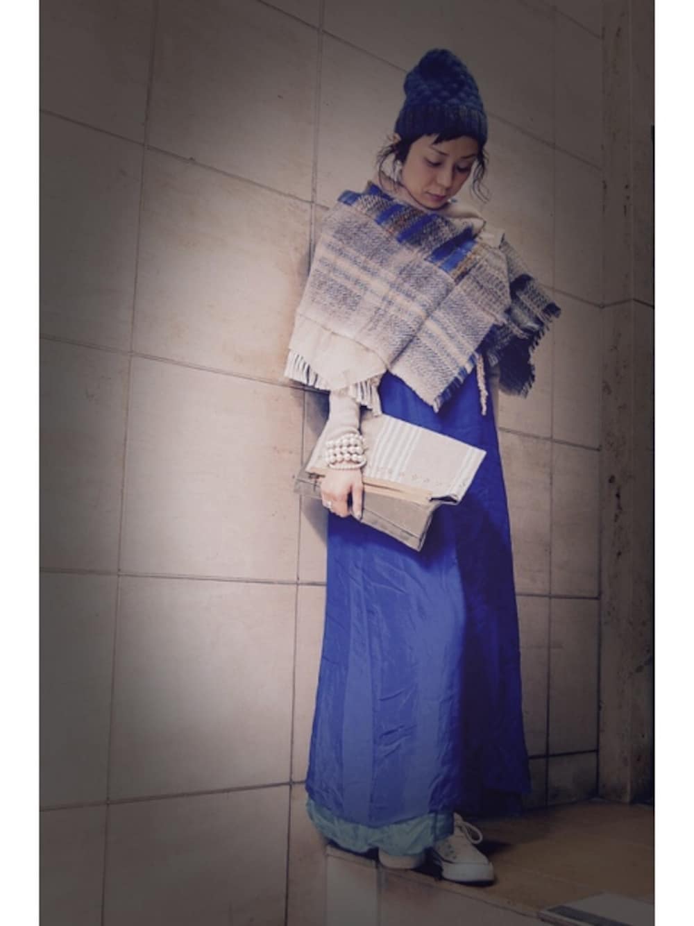 ブルー系のワンピース、ベージュ系のクラッチバッグ、ブルー系のマフラーを着用したレディースの秋コーディネートの1枚目の写真