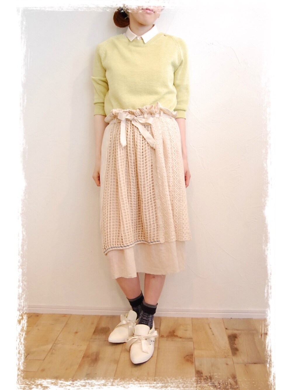 グリーン系のニット/セーター、ホワイト系のシャツ/ブラウス、ベージュ系のスカートを着用したレディースの春コーディネートの1枚目の写真