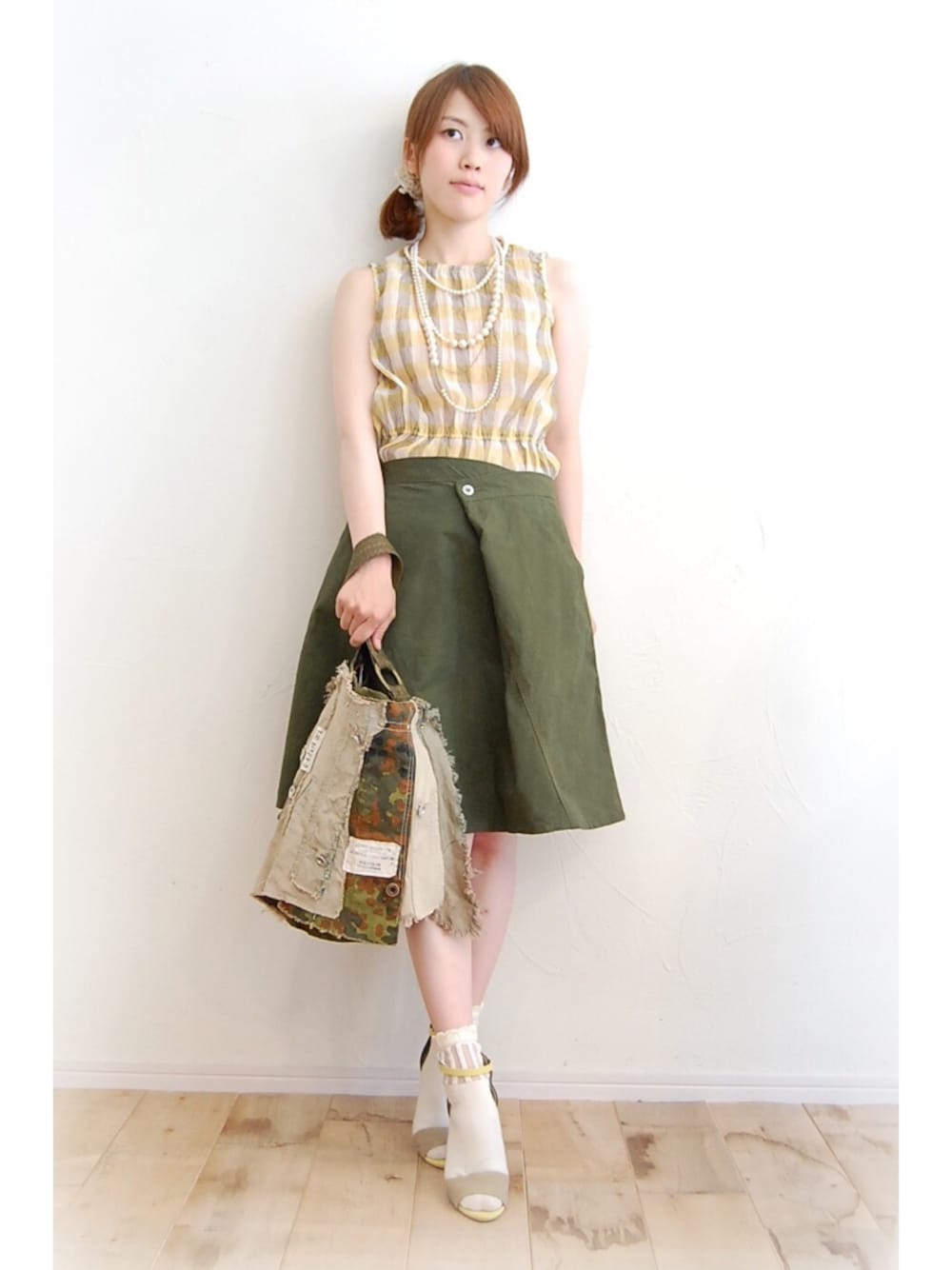 イエロー系のシャツ/ブラウス、グリーン系のスカート、ベージュ系のトートバッグを着用したレディースの夏コーディネートの1枚目の写真