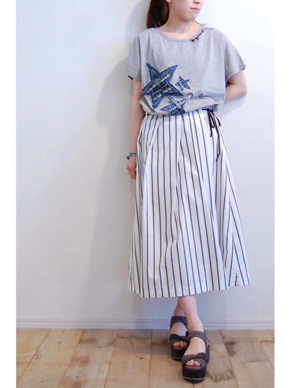 グレー系のTシャツ/カットソー、グレー系のサンダル、ホワイト系のスカートを着用したレディースの春コーディネートの1枚目の写真