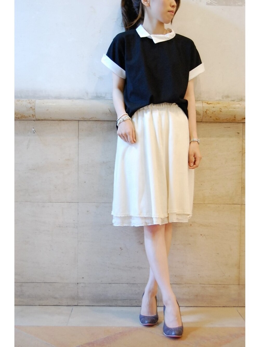 ブラック系のシャツ/ブラウス、ホワイト系のスカート、ブルー系のパンプスを着用したレディースの夏コーディネートの1枚目の写真