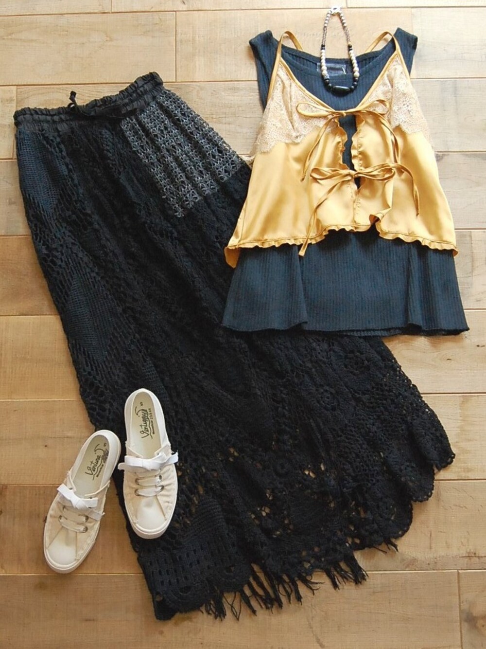 ゴールド系のキャミソール、ブラック系のスカート、ホワイト系のスニーカーを着用したレディースの夏コーディネートの1枚目の写真
