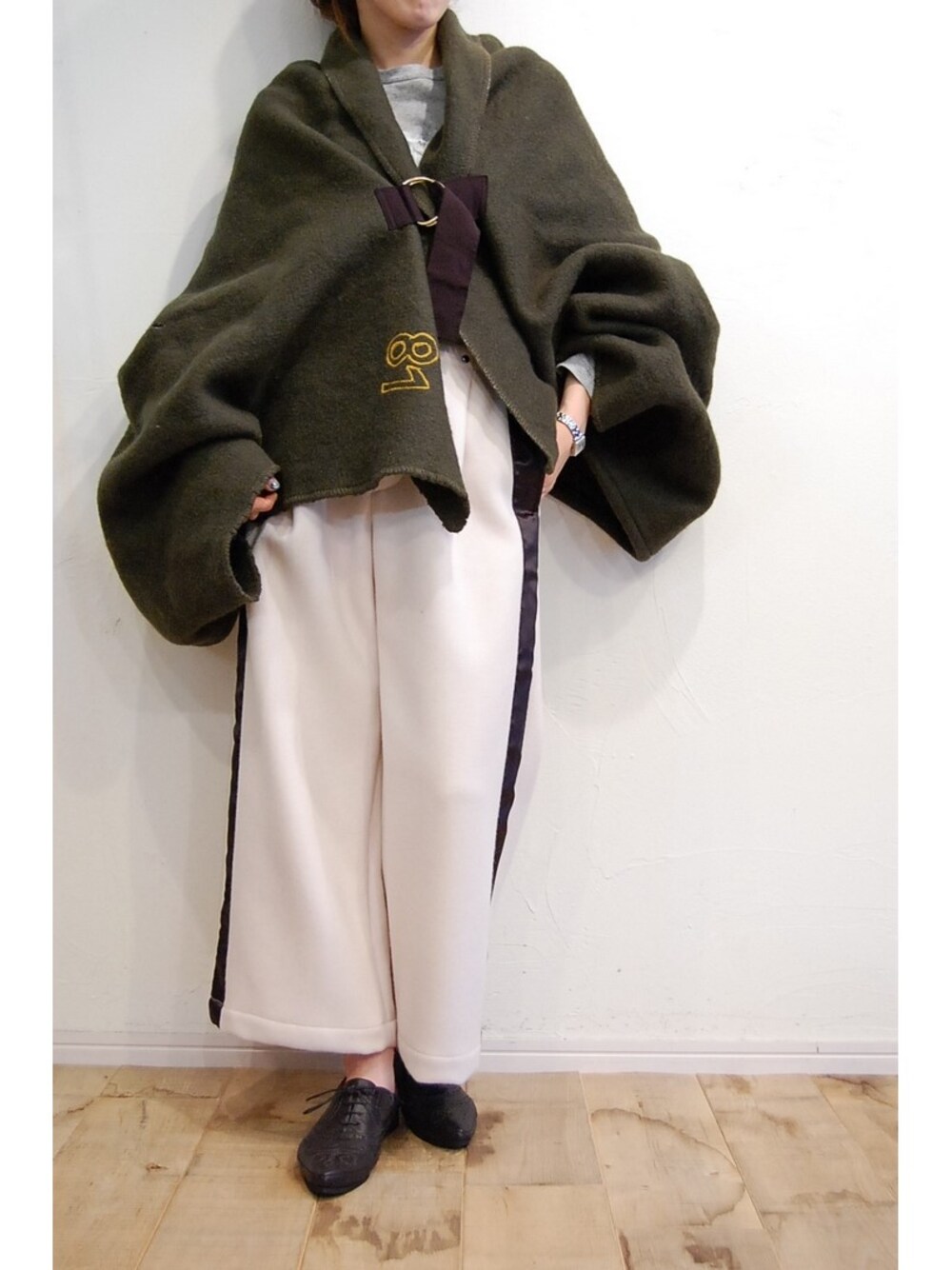 ホワイト系のその他パンツ、グリーン系のポンチョ、ブラック系のその他シューズを着用したレディースの秋コーディネートの1枚目の写真