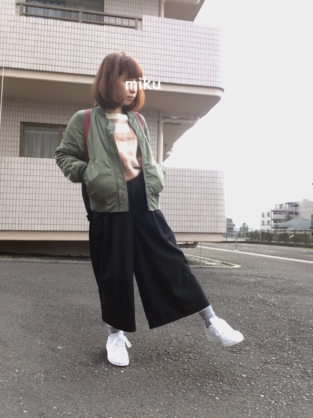 ブラック系のその他パンツ、ホワイト系のスニーカー、グリーン系のミリタリージャケットを着用したレディースの冬コーディネートの1枚目の写真