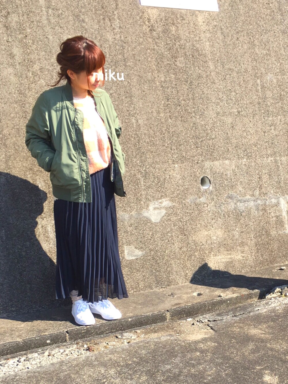 グリーン系のミリタリージャケット、ピンク系のニット/セーター、ブルー系のスカートを着用したレディースの春コーディネートの1枚目の写真