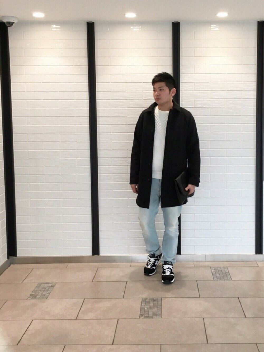 ブラック系のスニーカー、ブルー系のデニムパンツ、ホワイト系のニット/セーターを着用したメンズの冬コーディネートの1枚目の写真