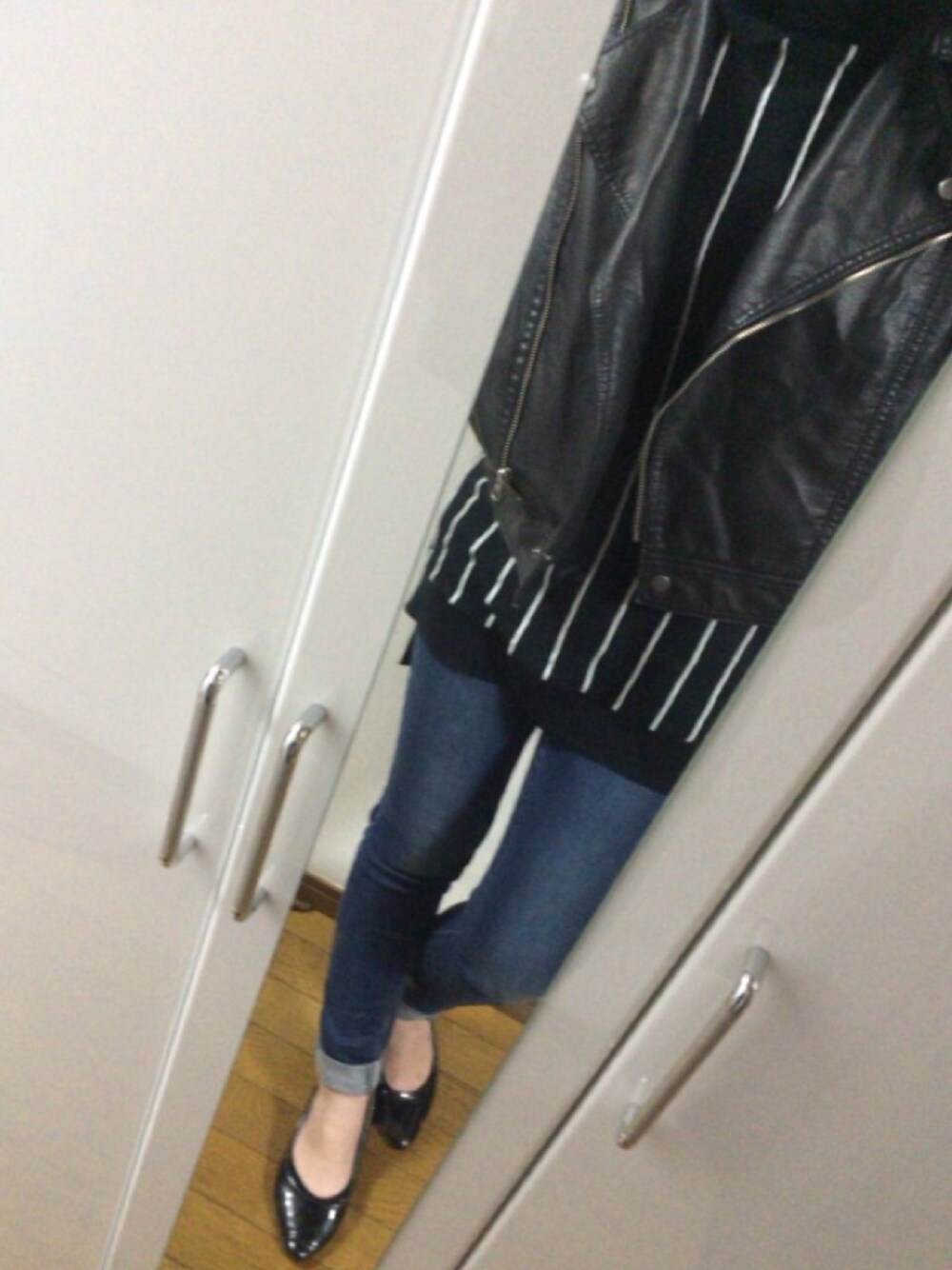 ブラック系のニット/セーター、ブルー系のデニムパンツ、ブラック系のライダースジャケットを着用したレディースの秋コーディネートの1枚目の写真