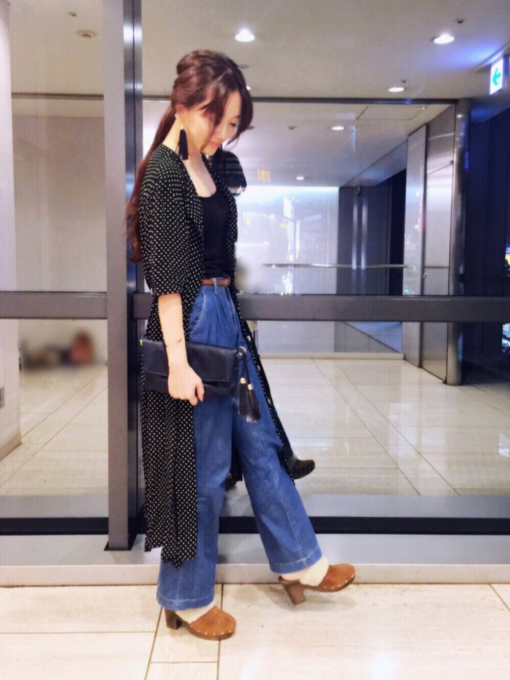 ブラック系のワンピース、ブルー系のショルダーバッグ、ブルー系のデニムパンツを着用したレディースの秋コーディネートの1枚目の写真