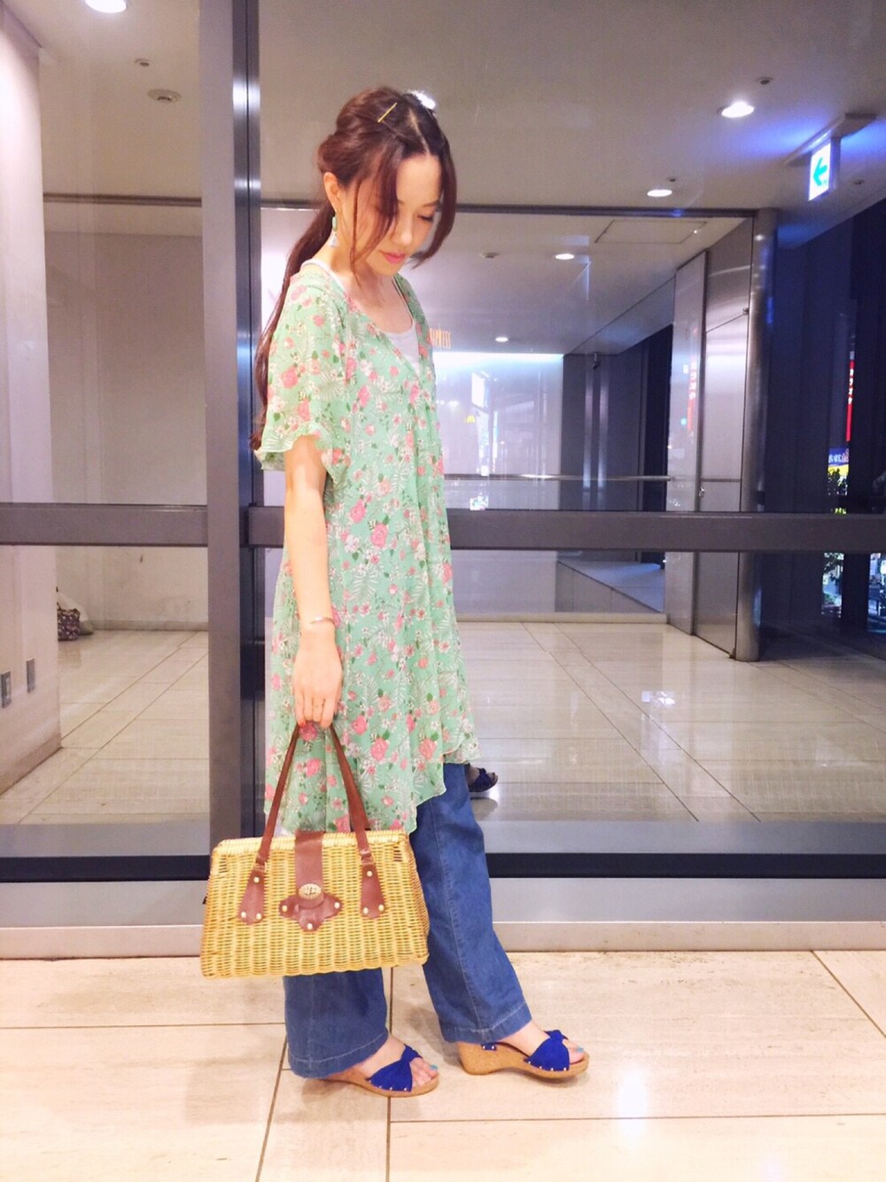 グリーン系のワンピース、ブラウン系のかごバッグ、ブルー系のサンダルを着用したレディースの秋コーディネートの1枚目の写真