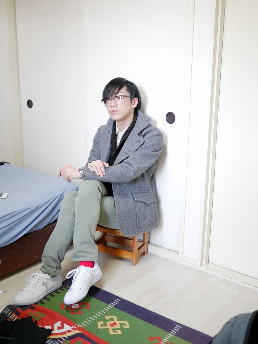 グレー系のピーコート、ブラック系のメガネを着用したメンズの春コーディネートの1枚目の写真