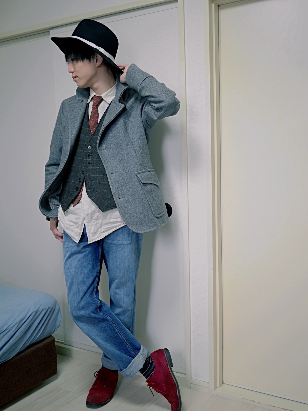 グレー系のピーコート、ブラウン系のベスト、ブラック系のハットを着用したメンズの春コーディネートの1枚目の写真