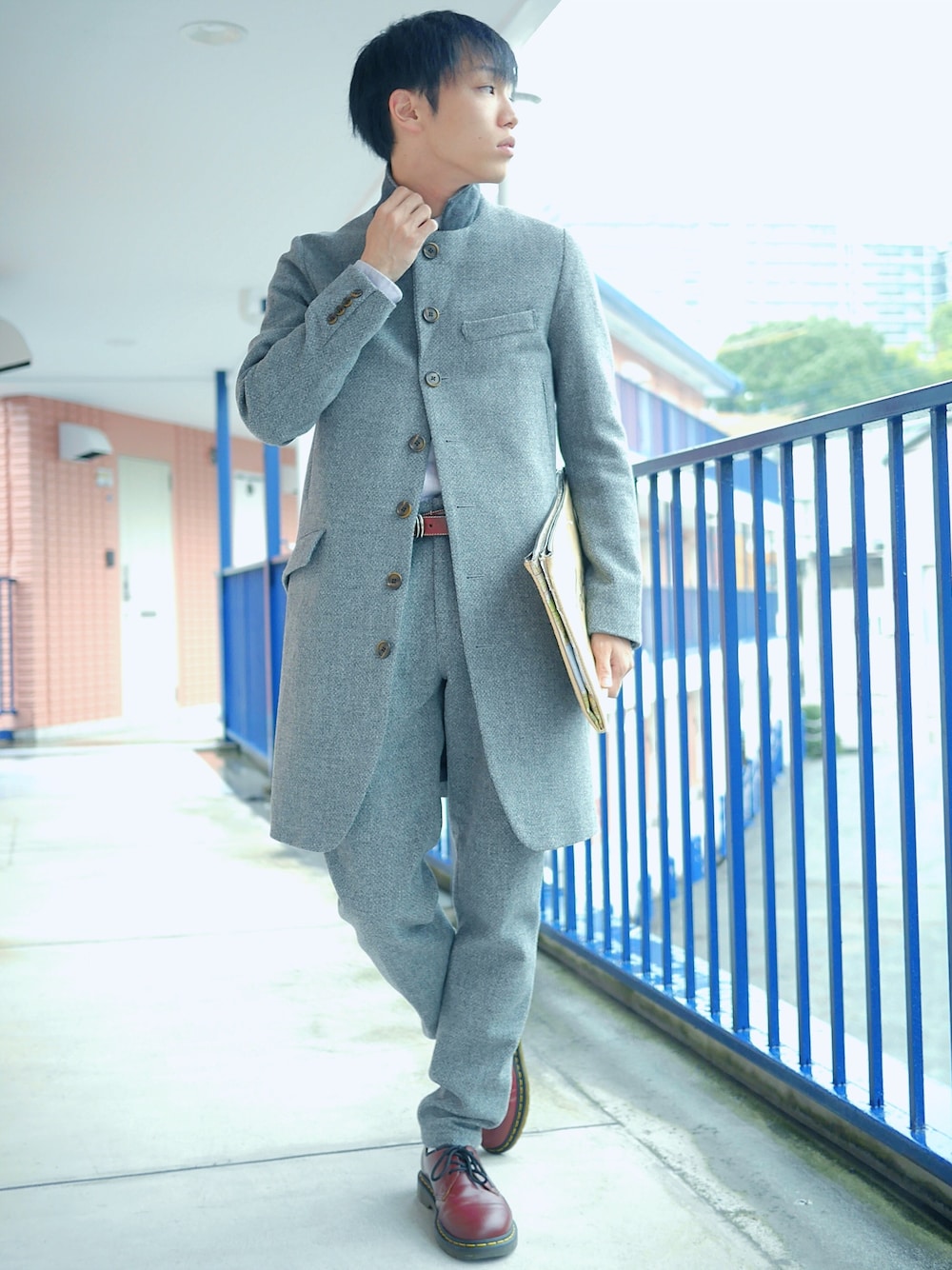 グレー系のチェスターコート、その他のクラッチバッグ、グレー系のスラックスを着用したメンズの秋コーディネートの1枚目の写真