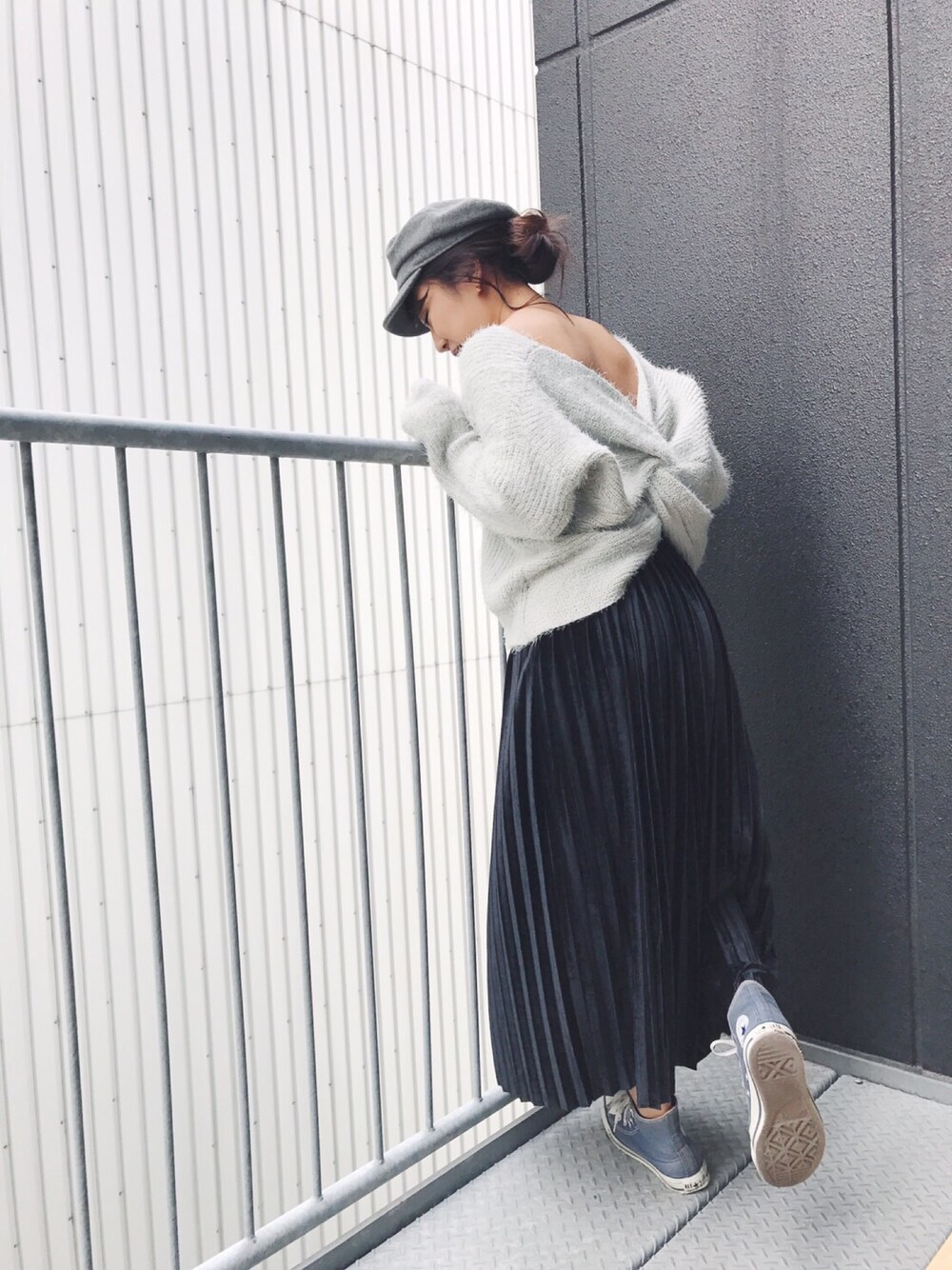 グレー系のニット/セーター、ブラック系のスカート、ブルー系のスニーカーを着用したレディースの秋コーディネートの1枚目の写真