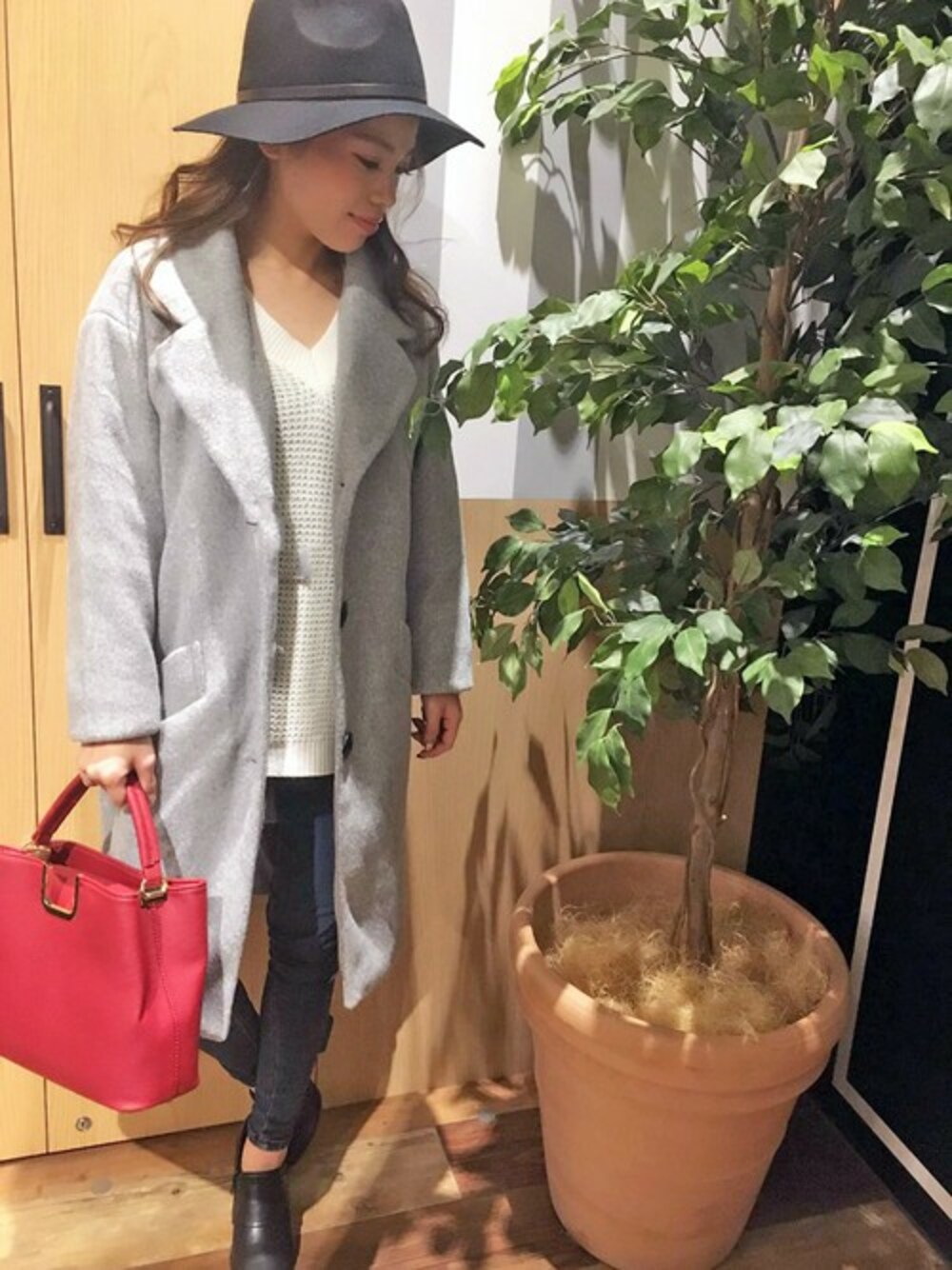 グレー系のチェスターコート、ホワイト系のニット/セーター、ブルー系のデニムパンツを着用したレディースの冬コーディネートの1枚目の写真