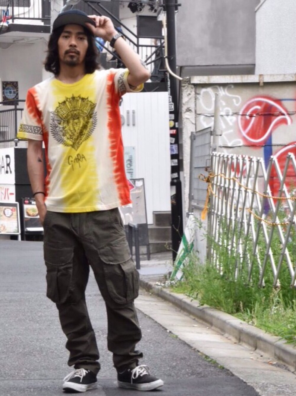 イエロー系のTシャツ/カットソー、グリーン系のパンツ、ブラック系のスニーカーを着用したメンズの夏コーディネートの1枚目の写真