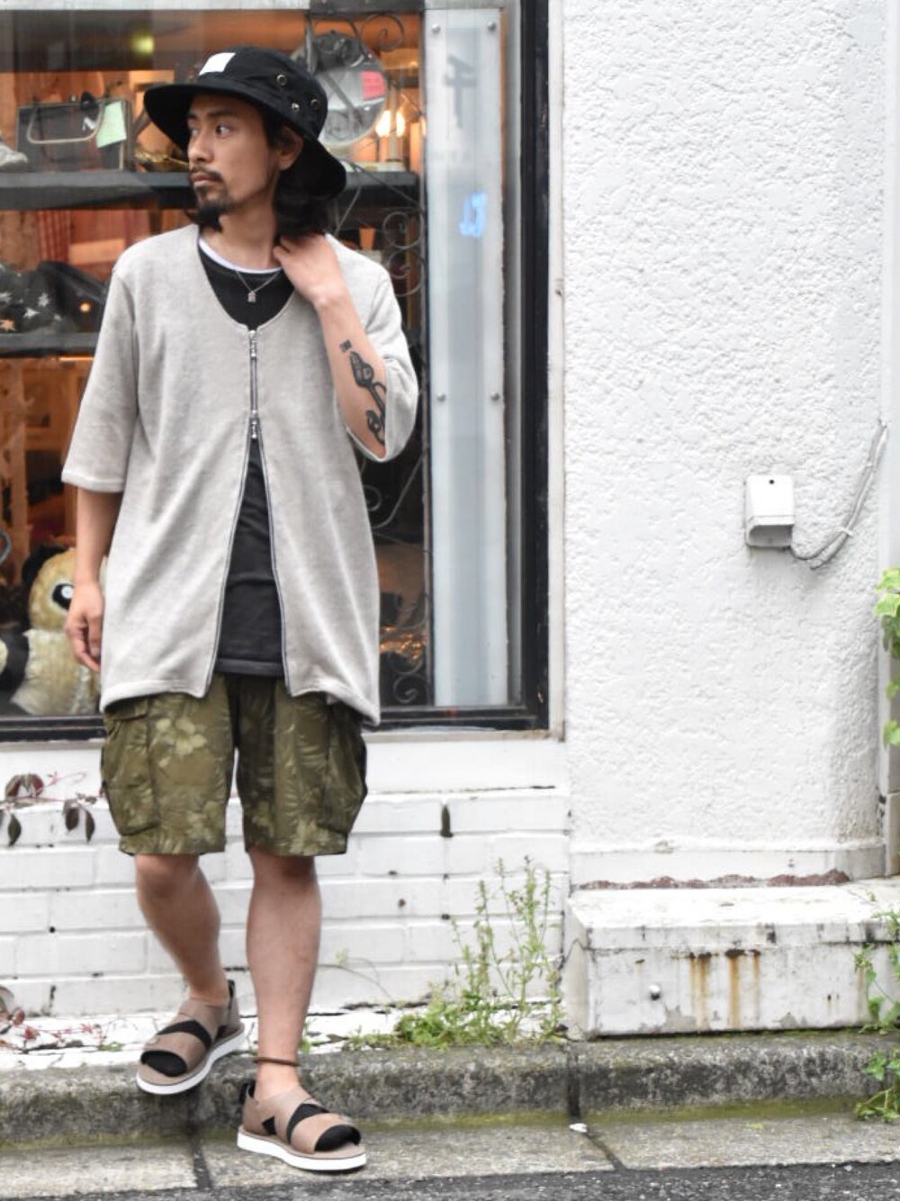 グリーン系のカーゴパンツ、ベージュ系のカーディガン/ボレロ、ブラック系のTシャツ/カットソーを着用したメンズの夏コーディネートの1枚目の写真