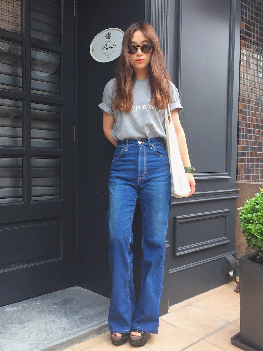 ブルー系のデニムパンツ、グレー系のTシャツ/カットソー、ブラウン系のサングラスを着用したレディースの夏コーディネートの1枚目の写真