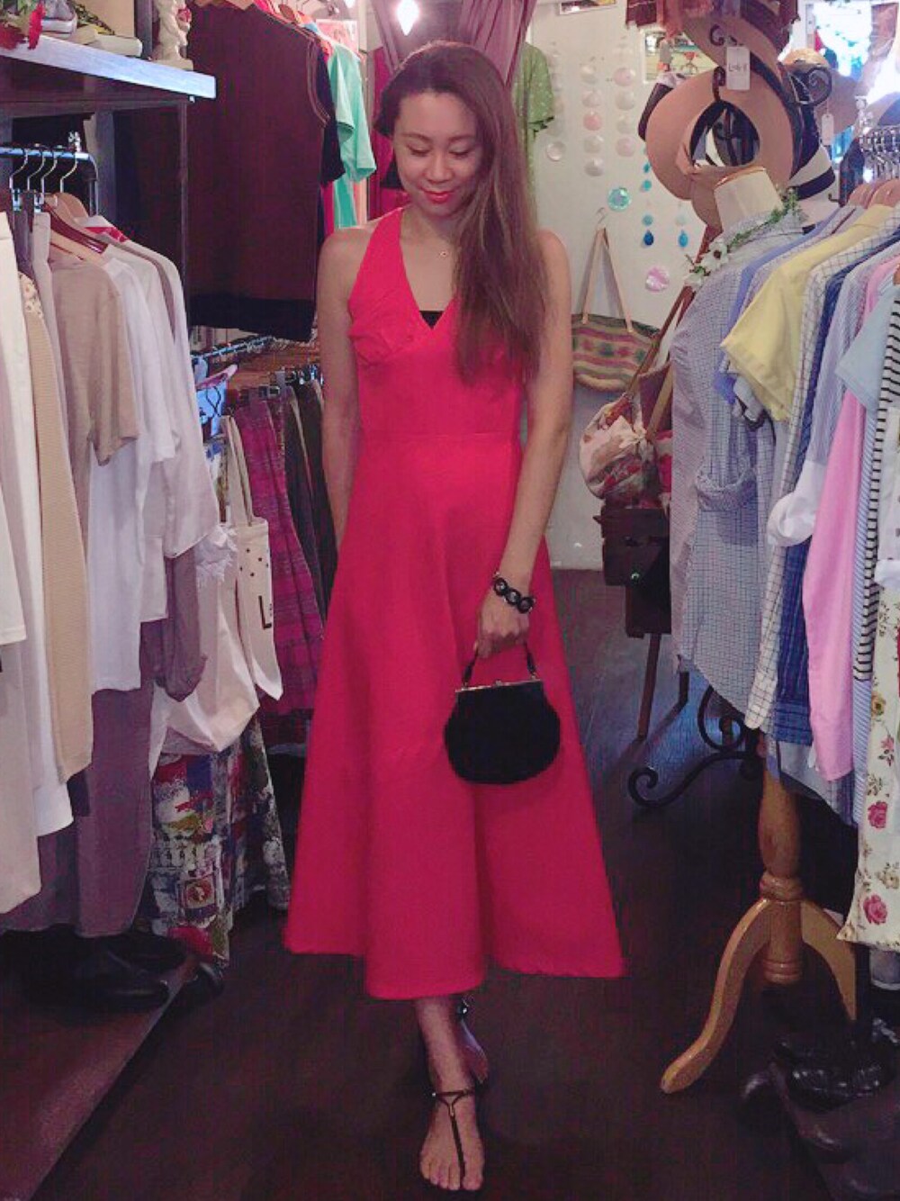 オレンジ系のワンピース、ブラック系のハンドバッグ、パープル系のブレスレットを着用したレディースの夏コーディネートの1枚目の写真