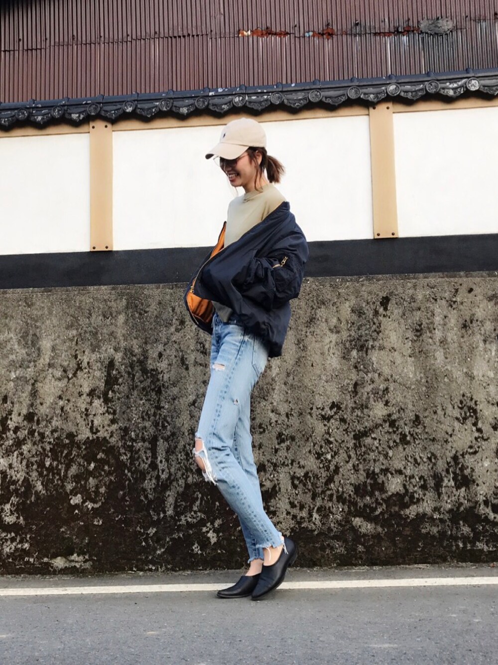 ブラック系のミリタリージャケット、ブルー系のデニムパンツ、ブラック系のブーティを着用したレディースの秋コーディネートの1枚目の写真