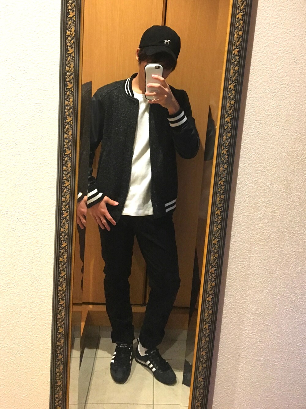 ブラック系のスタジャン、ブラック系のデニムパンツ、ブラック系のスニーカーを着用したメンズの秋コーディネートの1枚目の写真