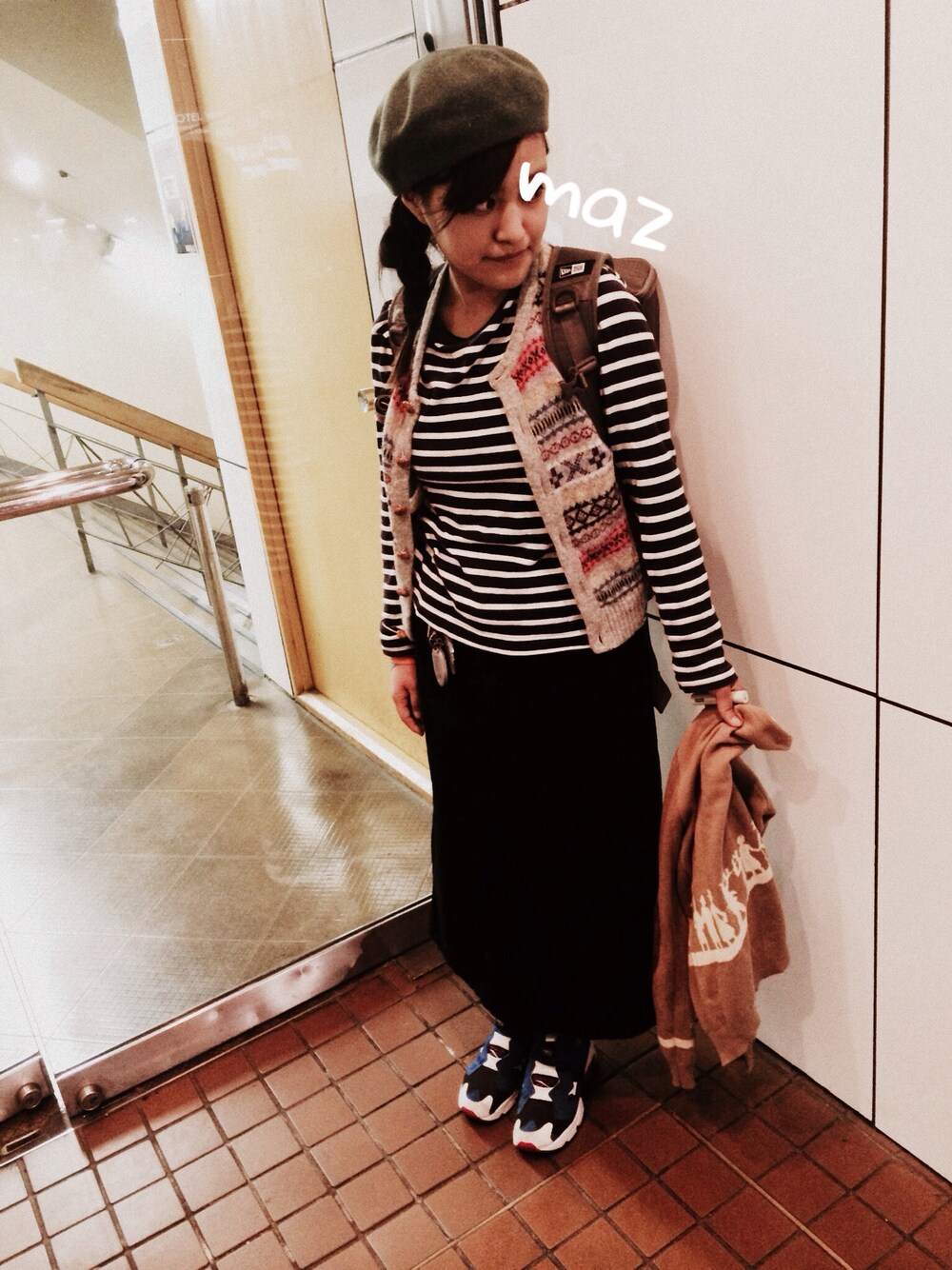 グレー系のベスト、グレー系のバックパック/リュック、ブルー系のスニーカーを着用したレディースの春コーディネートの1枚目の写真