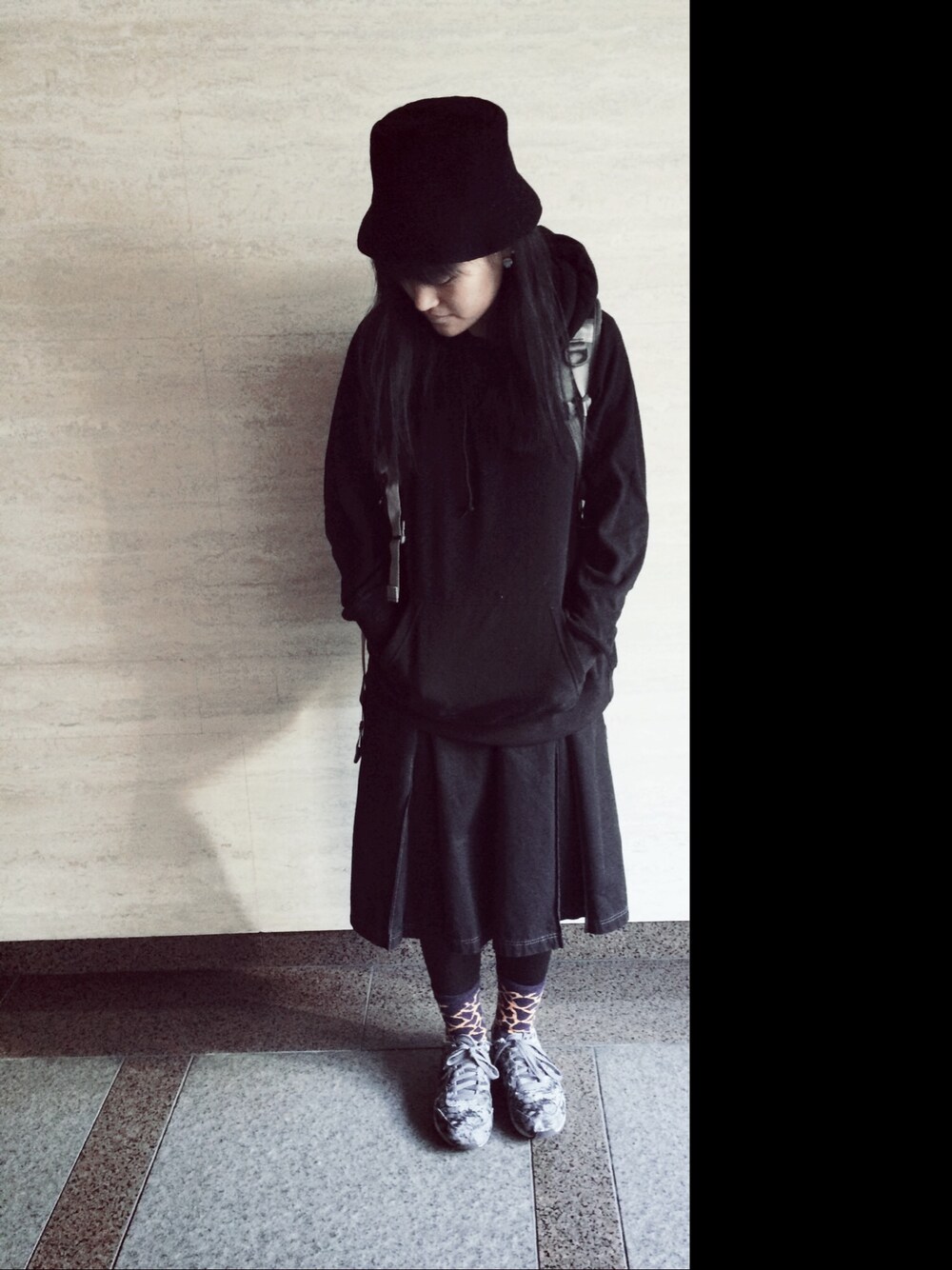 ブラック系のパーカー、ブラック系のスカート、グレー系のスニーカーを着用したレディースの冬コーディネートの1枚目の写真