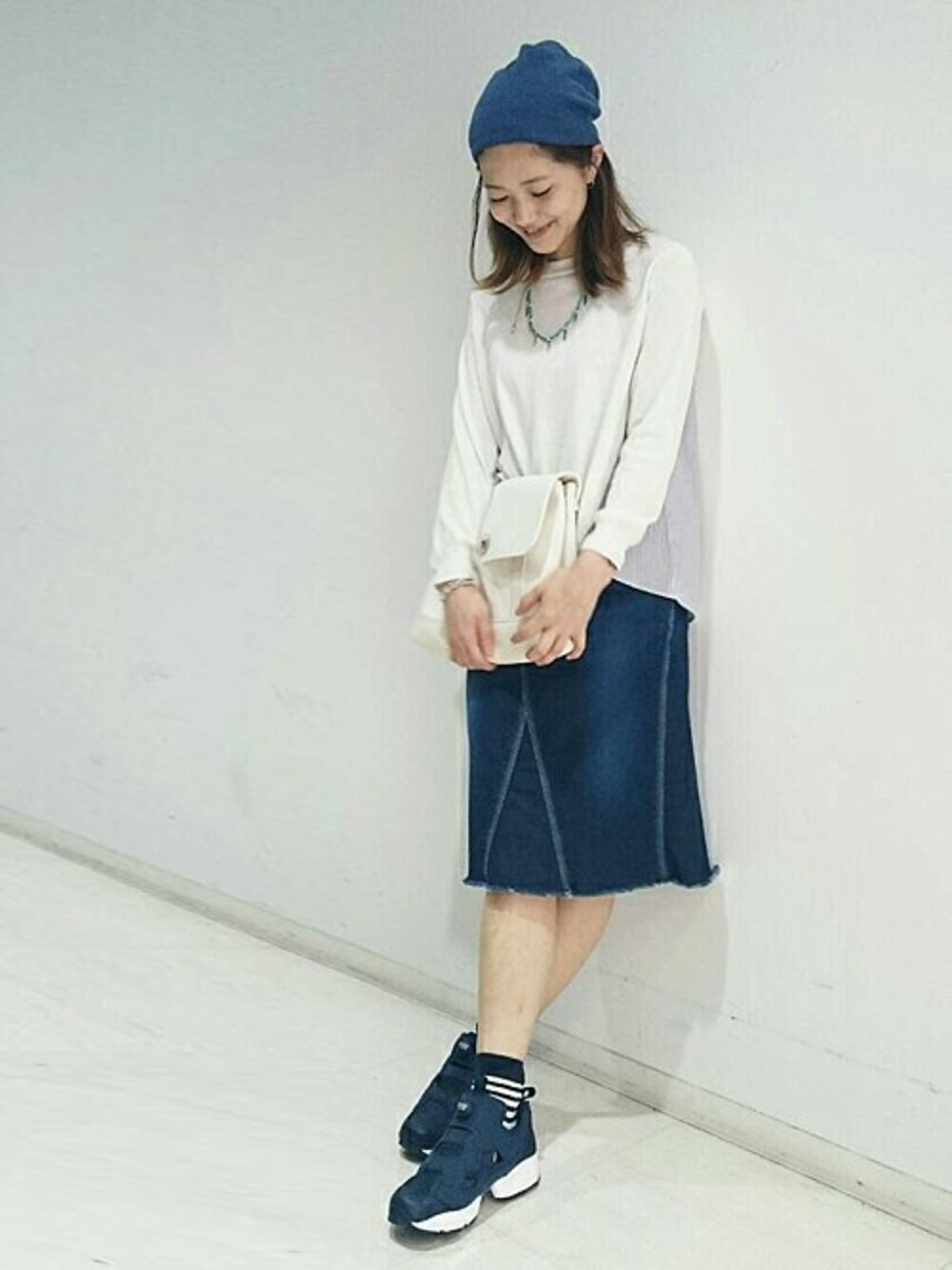 ブルー系のスニーカー、ホワイト系のクラッチバッグ、ブルー系のデニムスカートを着用したレディースの春コーディネートの1枚目の写真