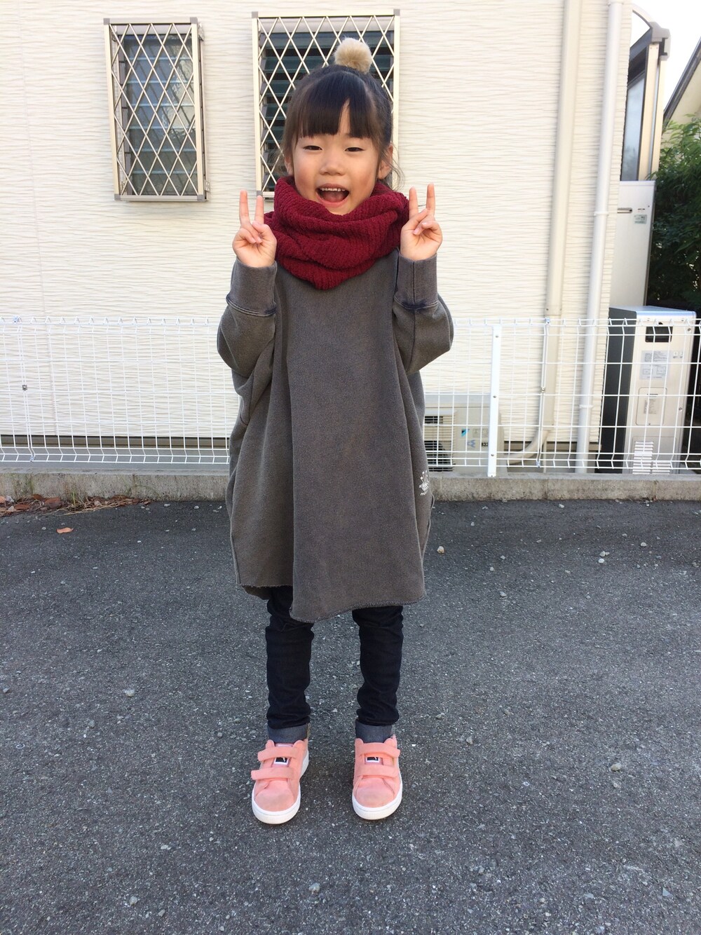 グレー系のワンピース、ブルー系のデニムパンツ、ピンク系のスニーカーを着用したキッズの秋コーディネートの1枚目の写真