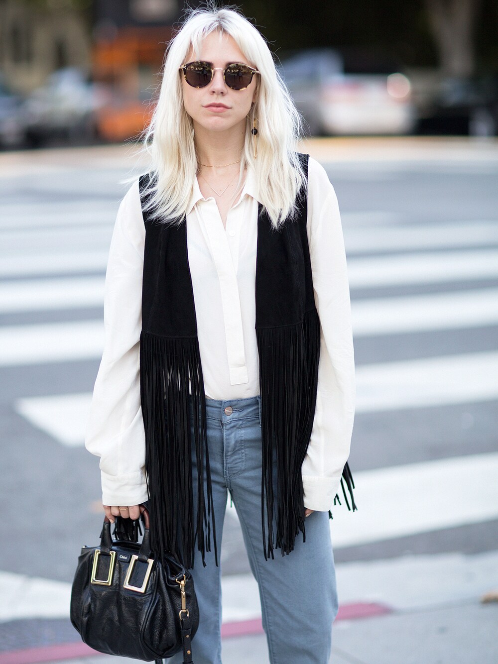 ブルー系のデニムパンツ、ブラック系のダウンベストを着用したレディースの春コーディネートの1枚目の写真