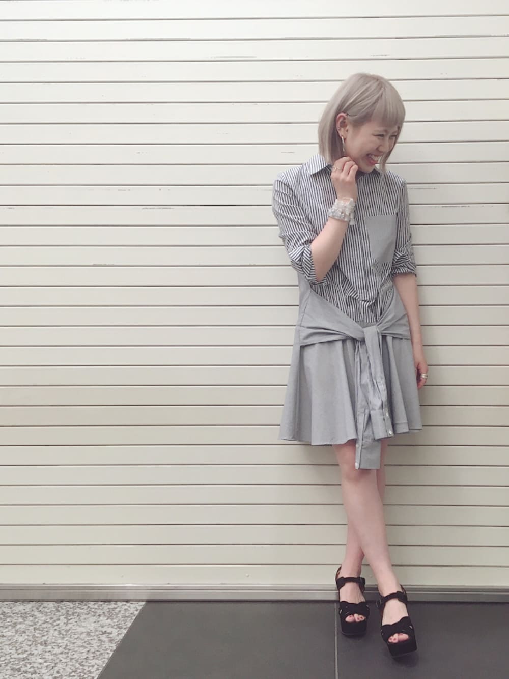 ブルー系のシャツワンピース、ブラック系のサンダル、ホワイト系のブレスレットを着用したレディースの夏コーディネートの1枚目の写真