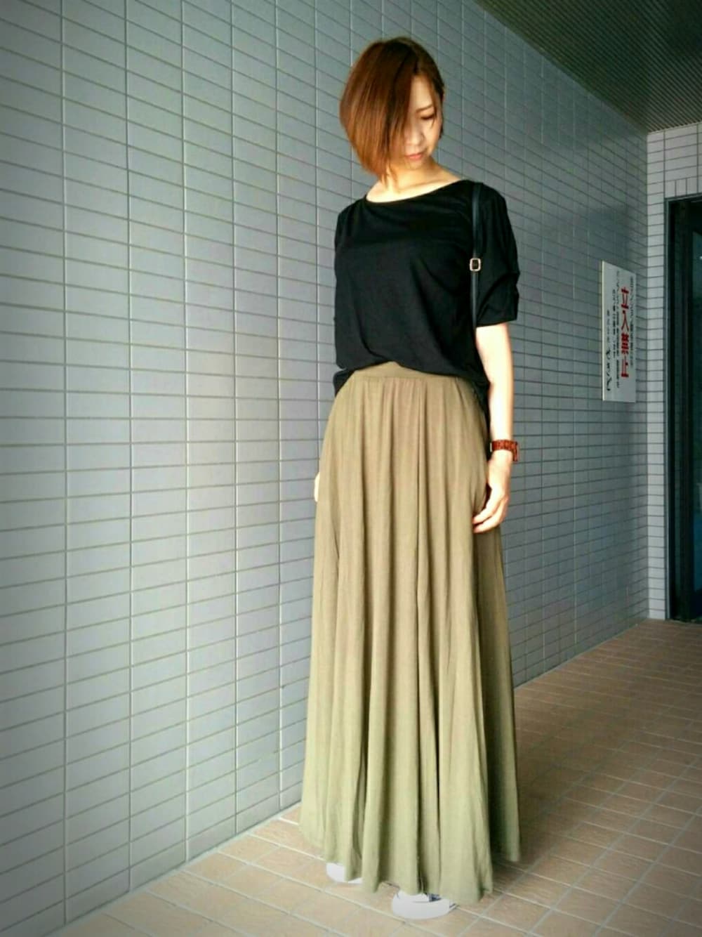 ブラック系のスニーカー、グリーン系のスカート、ブラック系のTシャツ/カットソーを着用したレディースの秋コーディネートの1枚目の写真