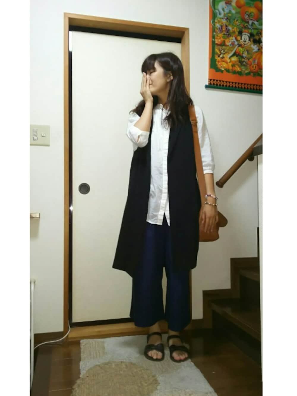 ブラック系のベスト、ブルー系のその他パンツ、ブラウン系のサンダルを着用したレディースの夏コーディネートの1枚目の写真