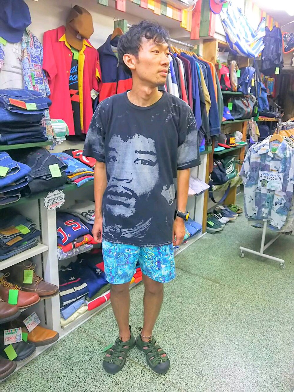 ブルー系のパンツ、ブラック系のトップス、グリーン系のシューズを着用したメンズの夏コーディネートの1枚目の写真