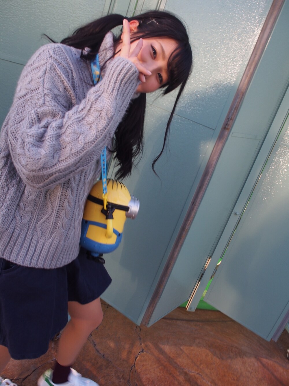 グレー系のニット/セーター、ブルー系のスカート、ホワイト系のスニーカーを着用したレディースの秋コーディネートの1枚目の写真