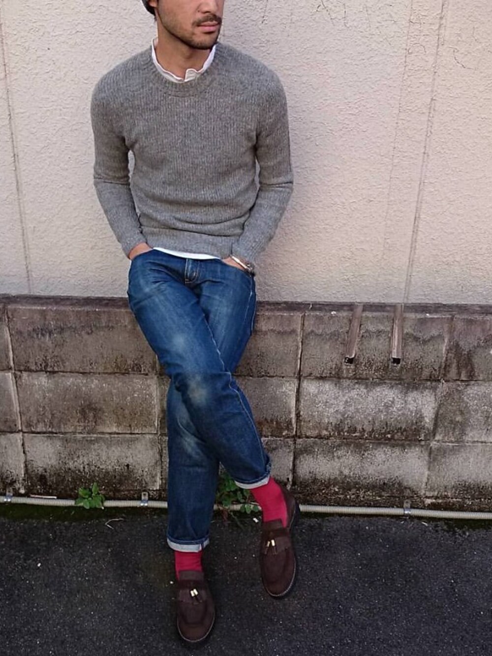 グレー系のニット/セーター、ホワイト系のTシャツ/カットソー、ブルー系のデニムパンツを着用したメンズの秋コーディネートの1枚目の写真
