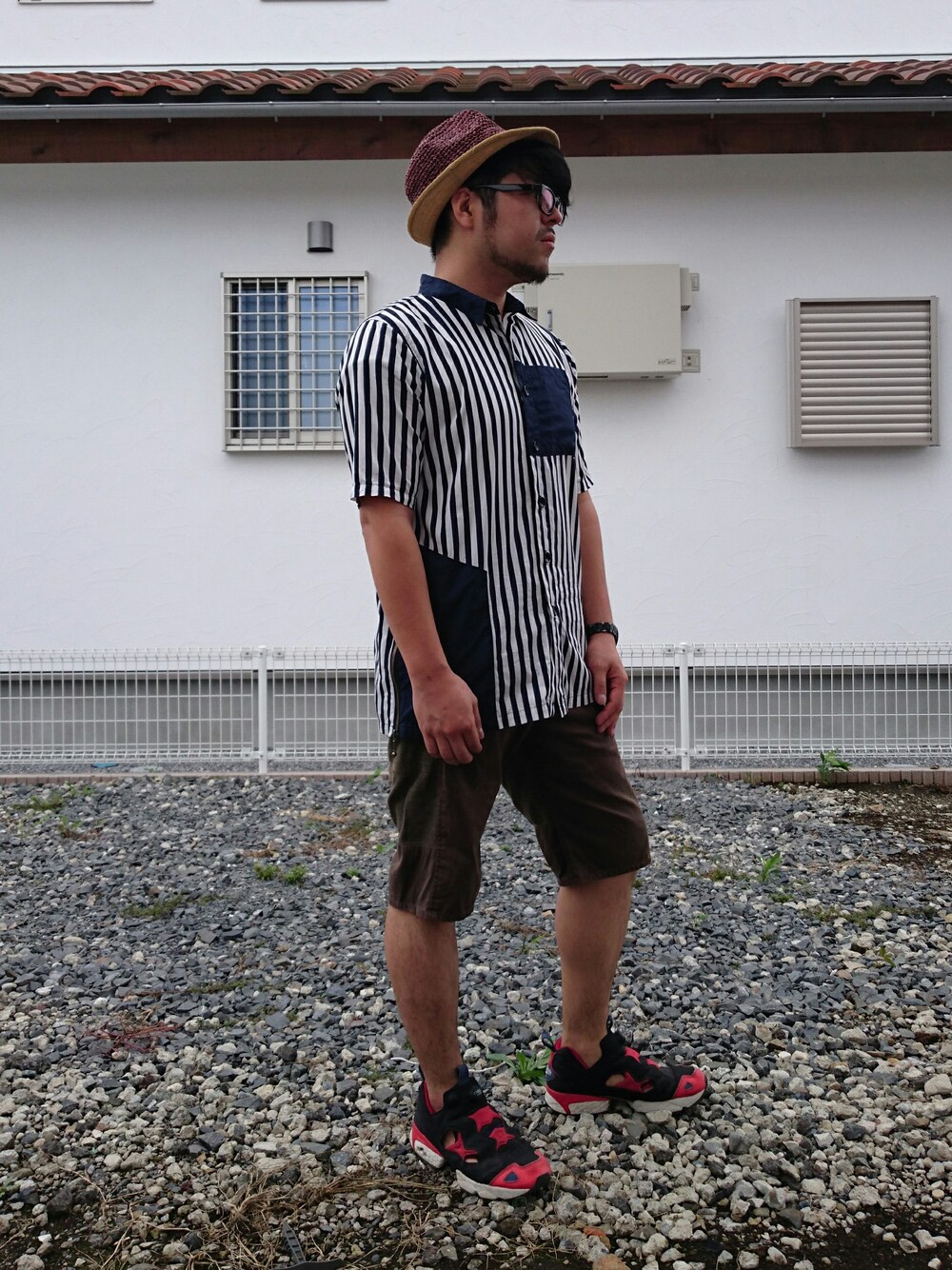 ベージュ系のトップス、ブラウン系のパンツ、ブラック系のスニーカーを着用したメンズの夏コーディネートの1枚目の写真