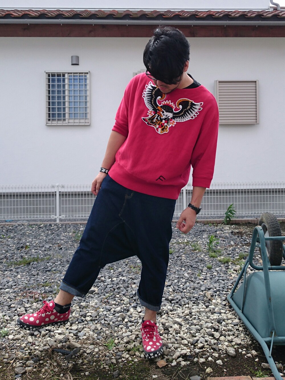 レッド系のTシャツ/カットソー、ブルー系のデニムパンツ、レッド系のスニーカーを着用したメンズの秋コーディネートの1枚目の写真