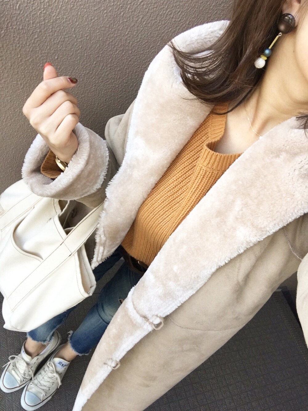 イエロー系のトップス、ブルー系のデニムパンツ、ホワイト系のバッグを着用したレディースの秋コーディネートの1枚目の写真