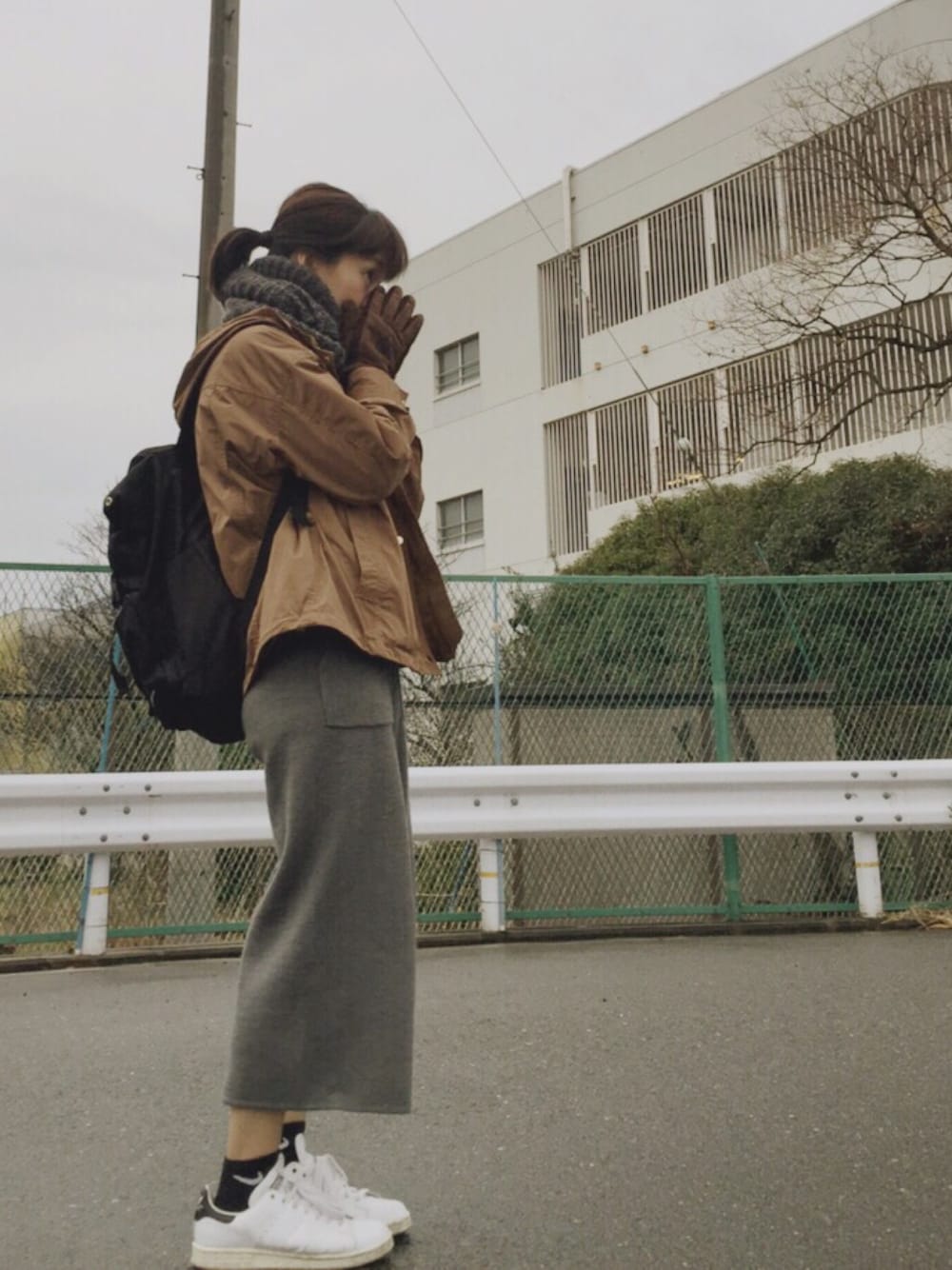 ブラウン系のマウンテンパーカー、ブラック系のスウェット、グレー系のパンツを着用したレディースの冬コーディネートの1枚目の写真