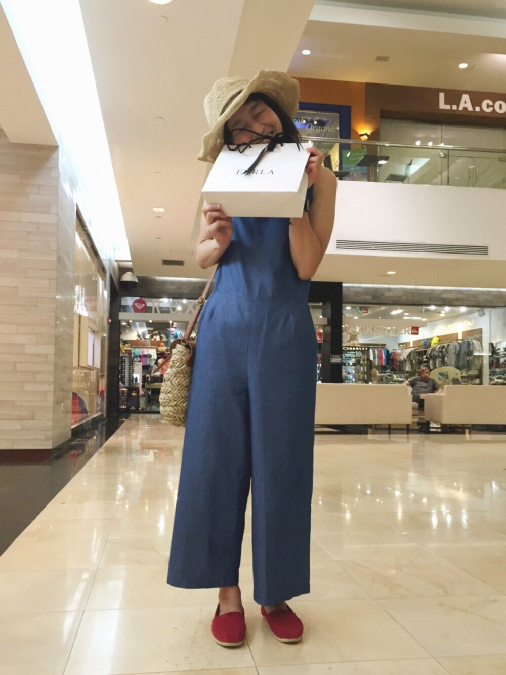 ブルー系のサロペット/オーバーオール、ベージュ系のショルダーバッグ、レッド系のスリッポンを着用したレディースの春コーディネートの1枚目の写真