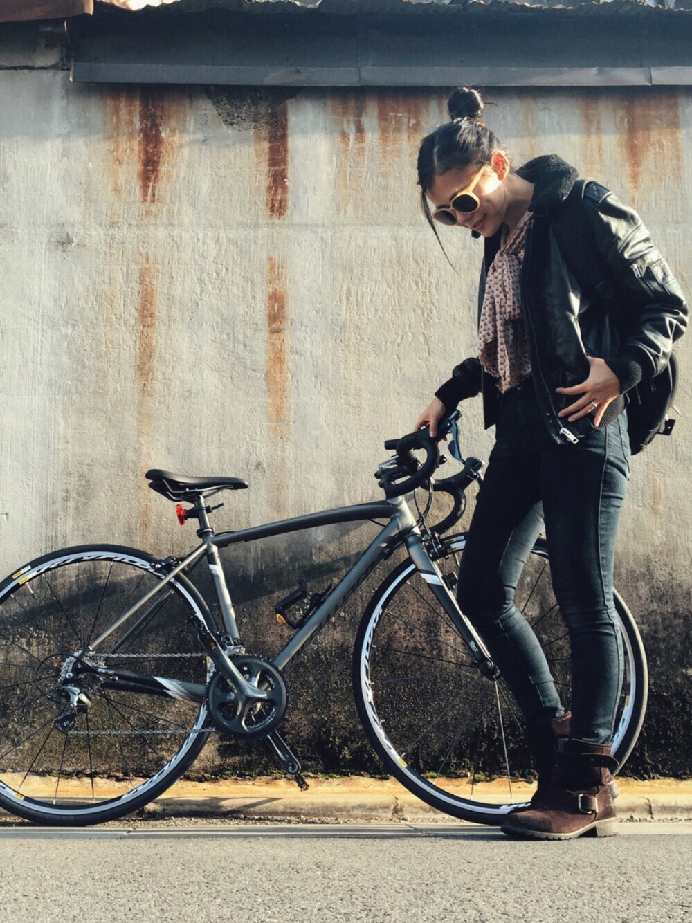 「ボウタイブラウス、ライダースジャケット、サングラス、革ジャン、エンジニアブーツ、自転車スタイル、バックパック」｜「SNIDELのカラフルフレームサングラス（サングラス、ベージュ系）」を使った、HAL さん（レディース・155cm）の秋コーディネートの1枚目の写真