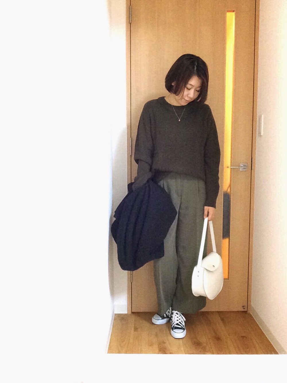 グリーン系のニット/セーター、グリーン系のスラックス、ブラック系のその他アウターを着用したレディースの秋コーディネートの1枚目の写真